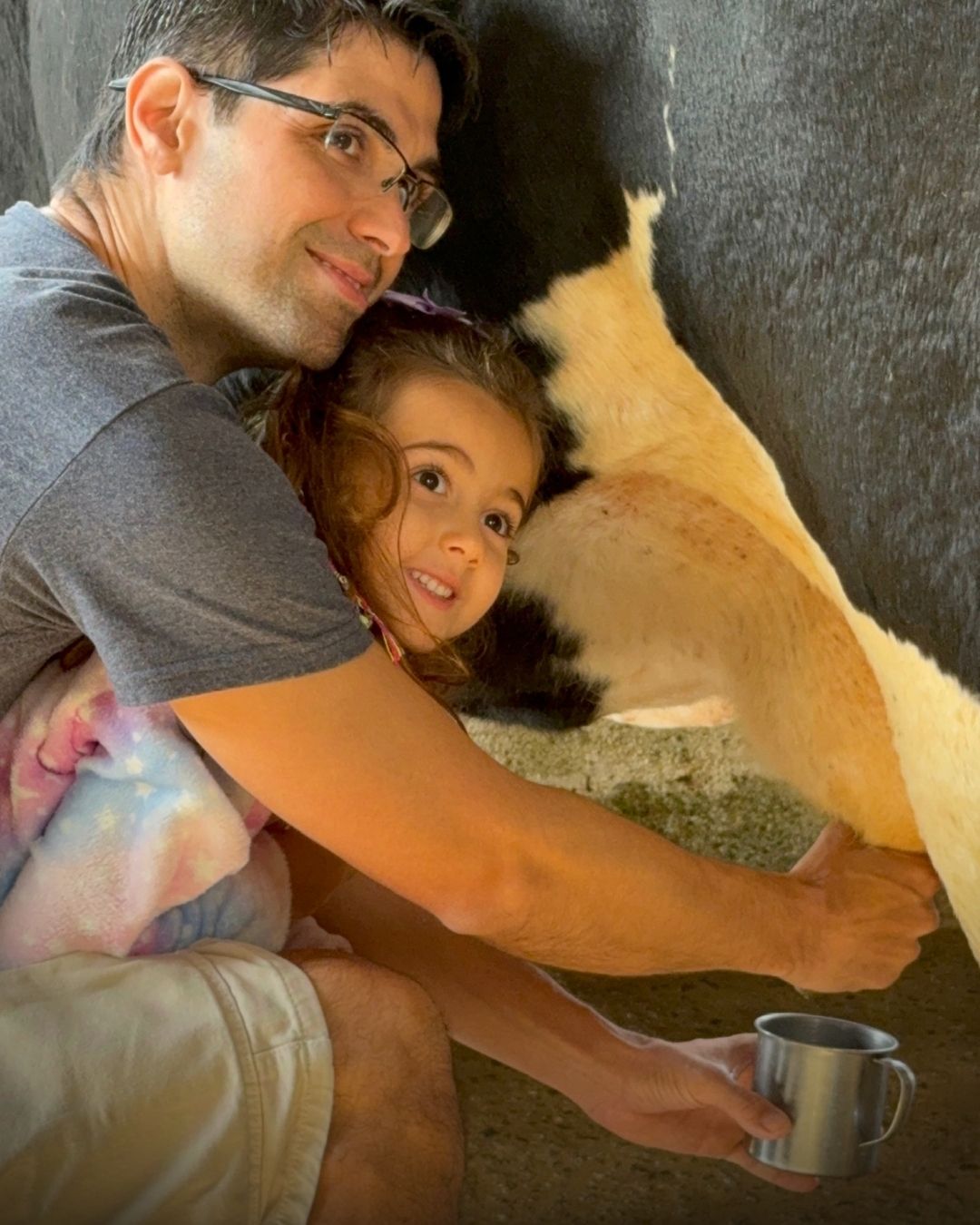 Pai e filha ordenhando a vaca